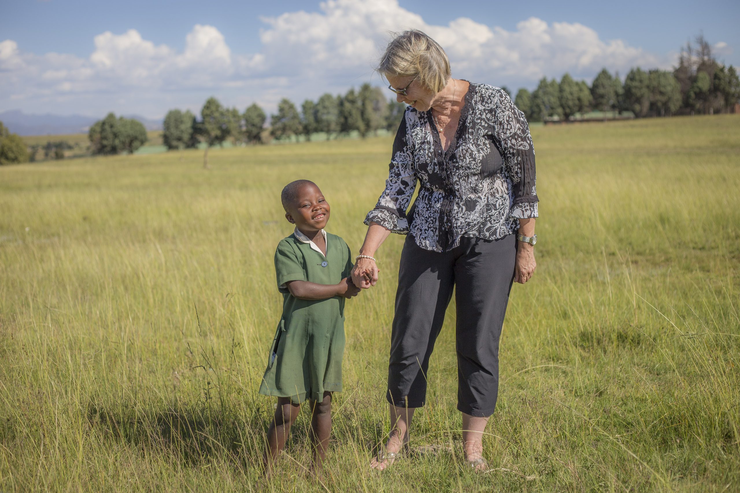 Dr. Peg Herbert walks with young Basotho girl through a field in Lesotho.