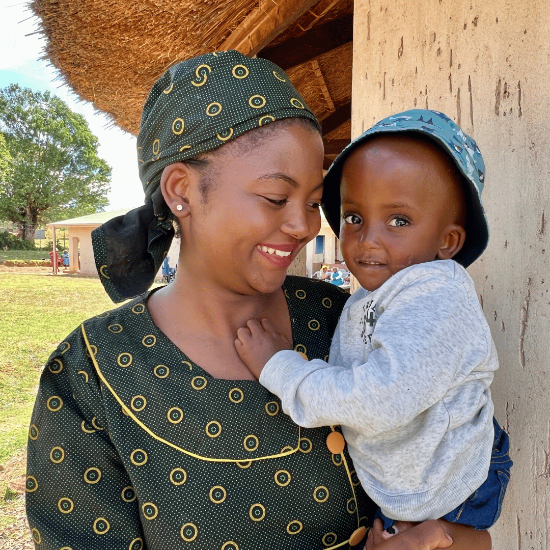 A young mother holds her little boy, smiling for the camera