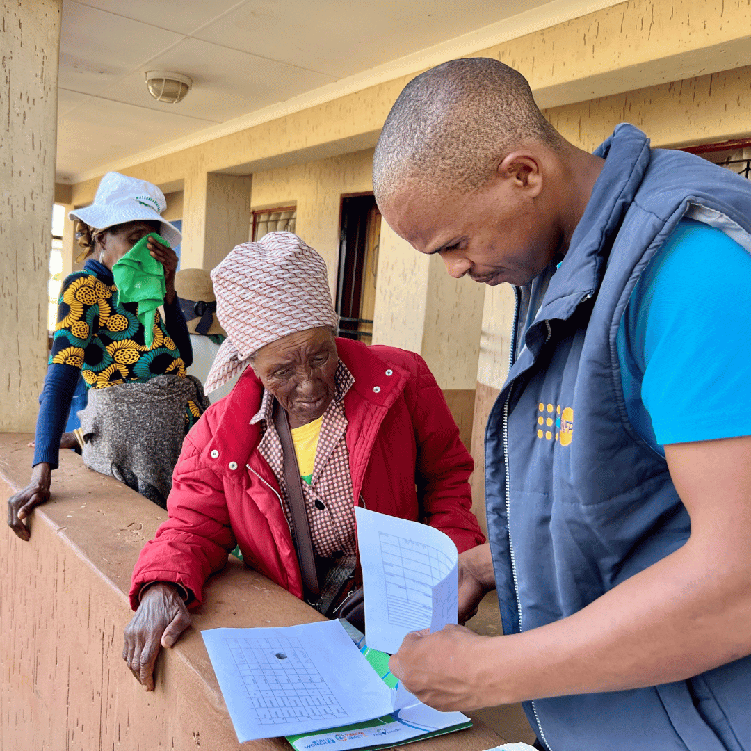 Help Lesotho staff member helping a grandmother fill out paperwork