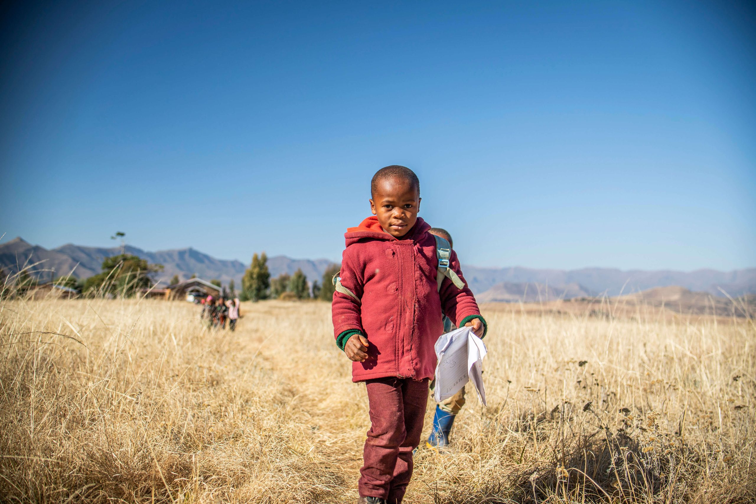 child walking through field in Lesotho on their way to the Pitseng Centre from a nearby school.