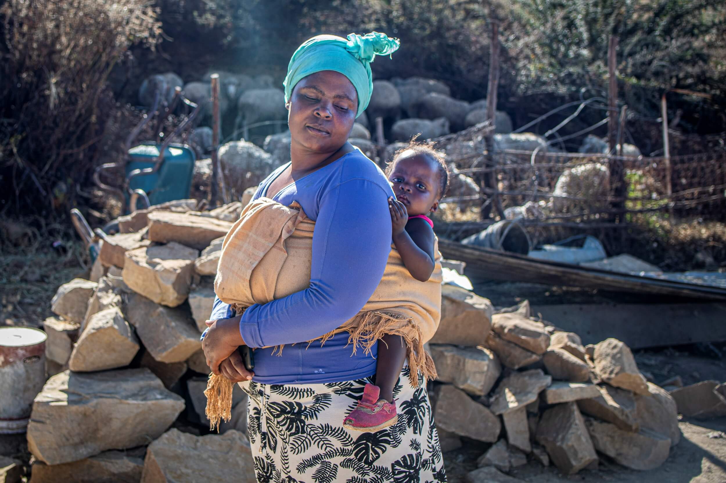 Basotho mother in blue scarf carrying a toddler